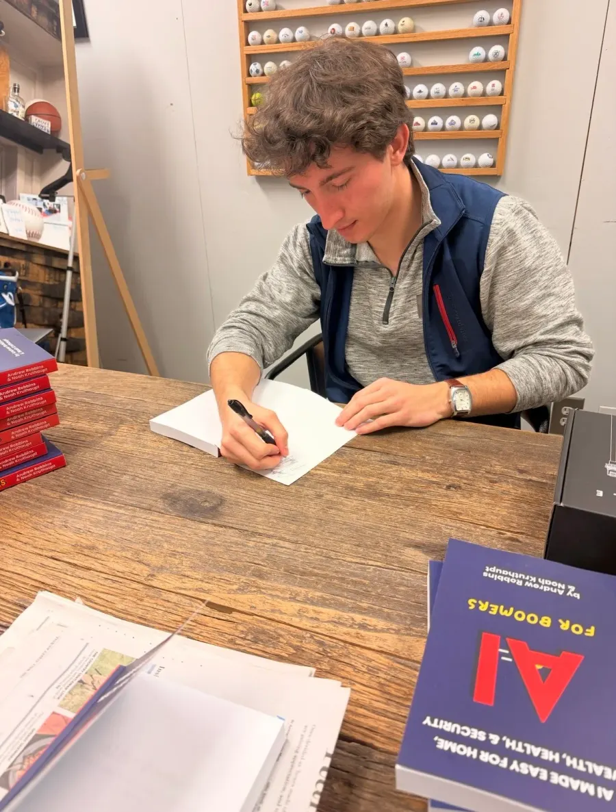 A copy of AI for Boomers being signed at a table